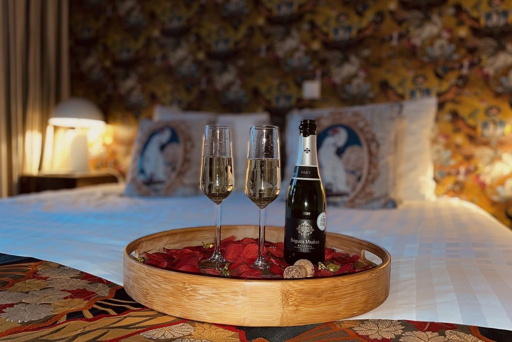 Cava in glasses in bed with rose petals at hotel Gold and Silver